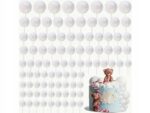 White globe string lights hang overhead above a pastel birthday cake with teddy bears on top, creating a festive backdrop, the scene soft and whimsical.