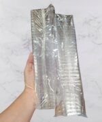 40eae08dc5009ab88a4563cab0abf3f9jpg › Udanewypieki Hand holding a tall stack of shiny aluminum loaf pans wrapped in plastic wrap.