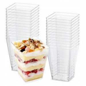 Stackable clear plastic dessert cups with square bases, shown with layered fruit-and-cream parfait in one cup used for individual servings.