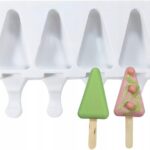White plastic popsicle mold tray with four slots and two decorated tree-shaped popsicles (green triangle and pink triangle) with drizzle icing