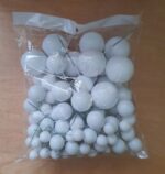 Clear bag filled with white decorative spheres of varying sizes, some with thin green stems, on a wooden surface.
